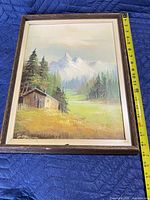 Front view of framed landscape painting with measuring tape