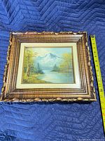 Front view of painting in carved frame with tape measure for scale