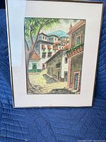 Framed watercolor street scene painting on blue blanket
