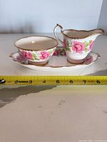 Front view of creamer, sugar bowl and tray with measuring tape showing length