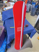 Snowboard deck side showing white stripes and tape measure for scale