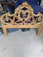 Front view of carved gilt wood queen headboard with scrollwork and attached legs