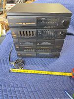 Front view of Sanyo DXD W57CD showing cassette decks, equalizer, tuner, CD player, and power cord