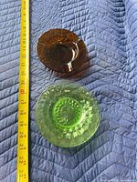 Amber ashtray beside one green saucer with tape measure