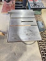 Top view of cast iron table surface with miter slot and blade opening showing rust and wear