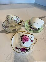 Three complete teacup and saucer sets displayed