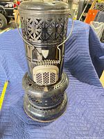 Front view of Valor cylindrical heater showing perforated body, grate door, handle and base