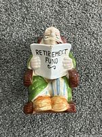 Front view showing elderly man reading newspaper labeled "RETIREMENT FUND"