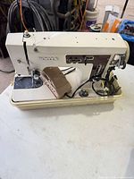 Front and top view of White model 1265 sewing machine seated in plastic case with foot pedal and cords