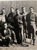 front of vintage snapshot showing 16 internees and placard 55