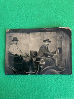 Front view of tintype showing two men in early car