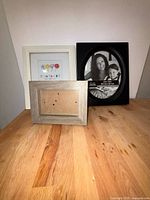 Three small frames: white floral print, silver empty frame, black oval Studio Décor frame