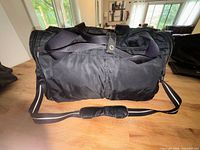 Full view of black Lululemon duffle showing shoulder strap and exterior slip pockets