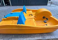Left side view of yellow-orange Equinox pedal boat showing blue seat backs and pedal cranks