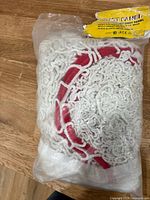 Bagged hockey shot panel net showing folded white polyester net with red pocket outlines