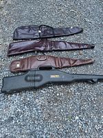 Four gun cases laid out, three soft vinyl and one Kolpin hard case