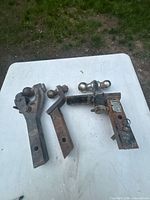 Three rusted adjustable trailer hitch mounts on table