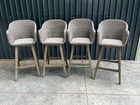 Front view of four matching wicker bar stools