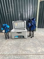 Cooler with lid open, two folded blue chairs