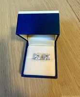 Earrings front view in box showing square crystals