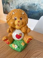 Front view of Brave Heart Lion ceramic coin bank on green base