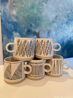 Five mugs stacked showing exterior black geometric patterns and handles