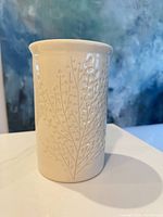 Front view of cream ceramic vase showing embossed leaf design