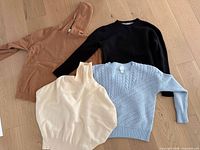 Four sweaters laid flat showing colors and styles