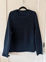 Front view of dark blue ribbed knit sweater on hanger
