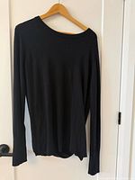 Front view of black long-sleeve knit sweater on hanger