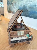 Three-quarter view showing piano form, hinged lid open, rotating bear figures, keyboard detail