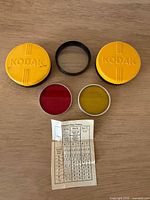 Lot overview showing two Kodak cases, two filters, Focar ring, paper insert