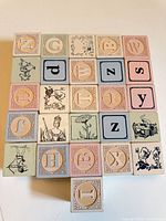 Front view of 25 blocks arranged in square formation plus one block protruding, showing letters and illustrations
