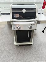 Full front view of Weber Spirit grill showing hood, thermometer, side shelves and cabinet base