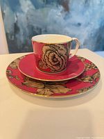 Cup stacked on saucer and plate showing color, pattern and gold trim