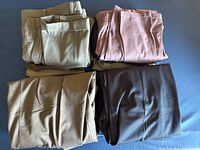 Four stacks of folded men’s pants in various solid colors on flat surface