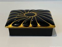 Top view of black ceramic trinket box with gold petal design