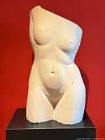 Front view of stone female torso sculpture on pedestal