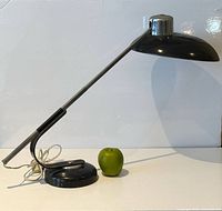 Side profile of chrome and black telescoping desk lamp with apple for scale