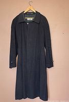 Front view of black Bugatti wool coat on hanger showing collar, button front, pockets, length