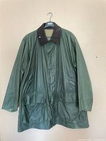 Full front view of green Barbour waxed jacket on hanger