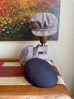 Three caps displayed, two brown tweed newsboy and one dark brown flat cap