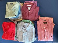 Stacked assortment of folded men’s shirts showing colours, patterns and visible labels