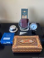 Group shot showing all items: wooden box, dominoes, coasters box, bell, glass holder with leather coasters, alarm clock, John Burton knife package