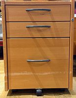 Front view showing three drawers, handles, casters, lock, scratches