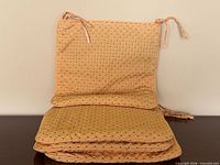 Stacked four yellow quilted seat cushions showing ties and quilting