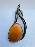 Front view of sterling pendant showing amber cabochon and silver frame