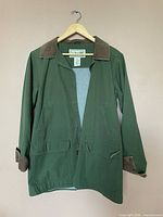 Full view of green jacket on hanger showing front, collar, pockets
