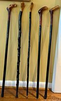 Five wooden walking sticks leaned against wall showing full length