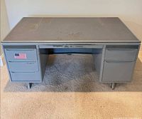 Front view of gray metal pedestal desk showing drawers and overall form